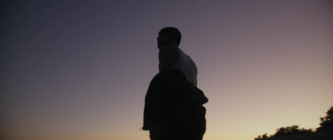 A soldier walking in an empty landscape looking around at sunset