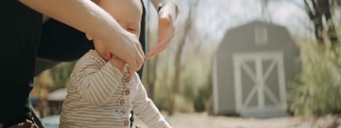 A mother picks up baby after the infant begins to eat dirt