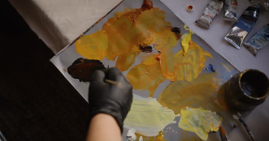 A person is using a paintbrush to move paint around on a paper