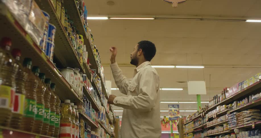 A man is looking at groceries in a store