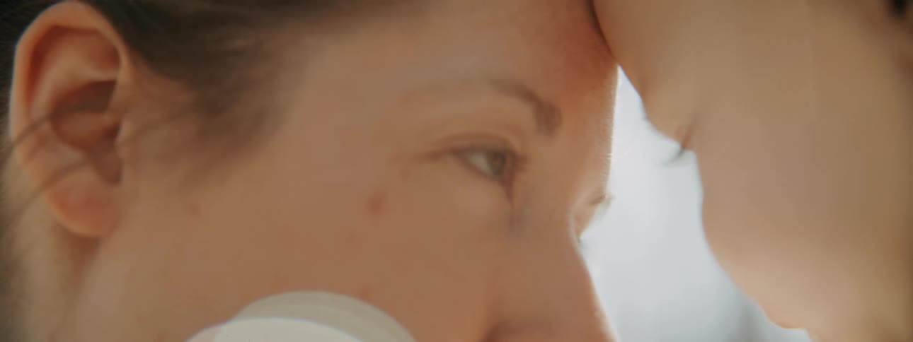 A mother tenderly kisses her baby in dreamy extreme close up