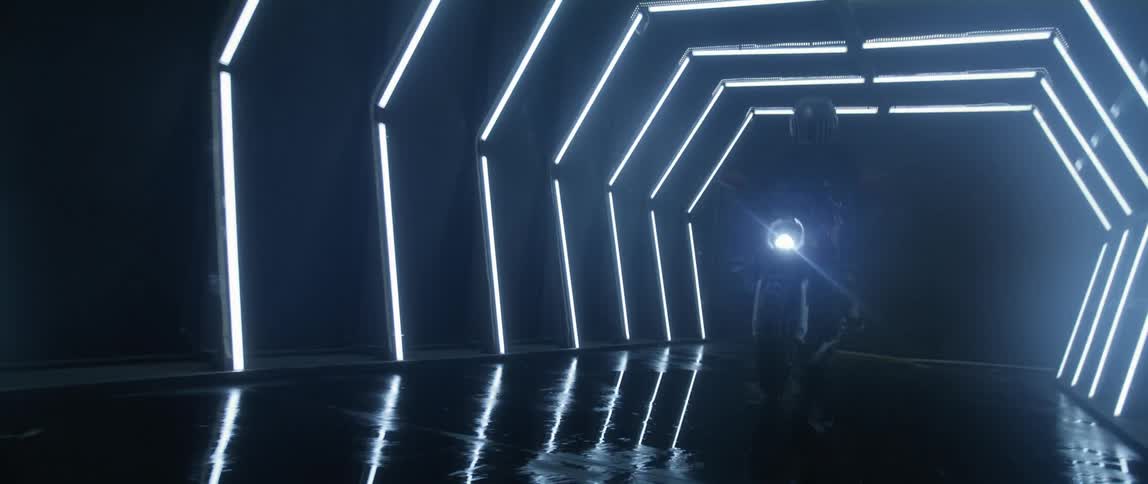A person drives a motorcycle through a tunnel with water at night