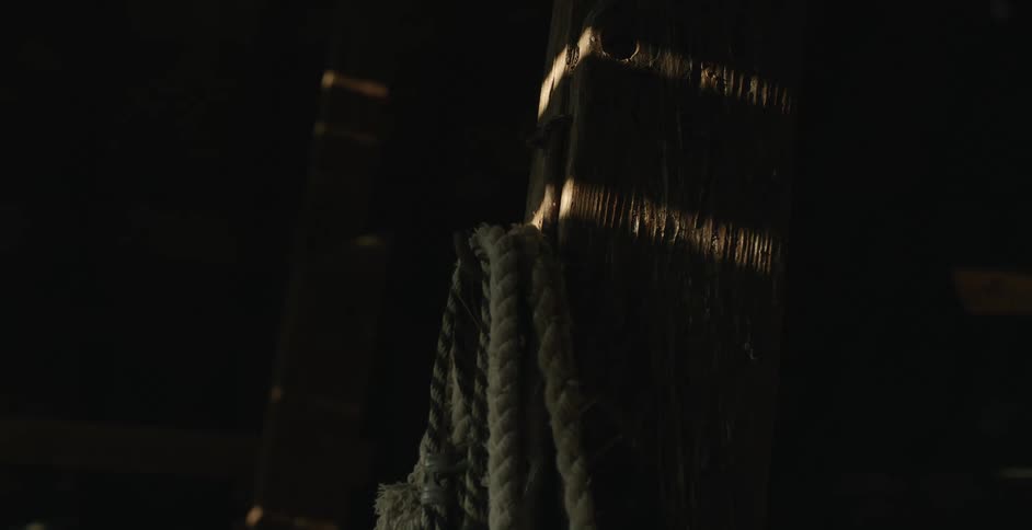 Rope hanging on a wood post indoors in a dark room