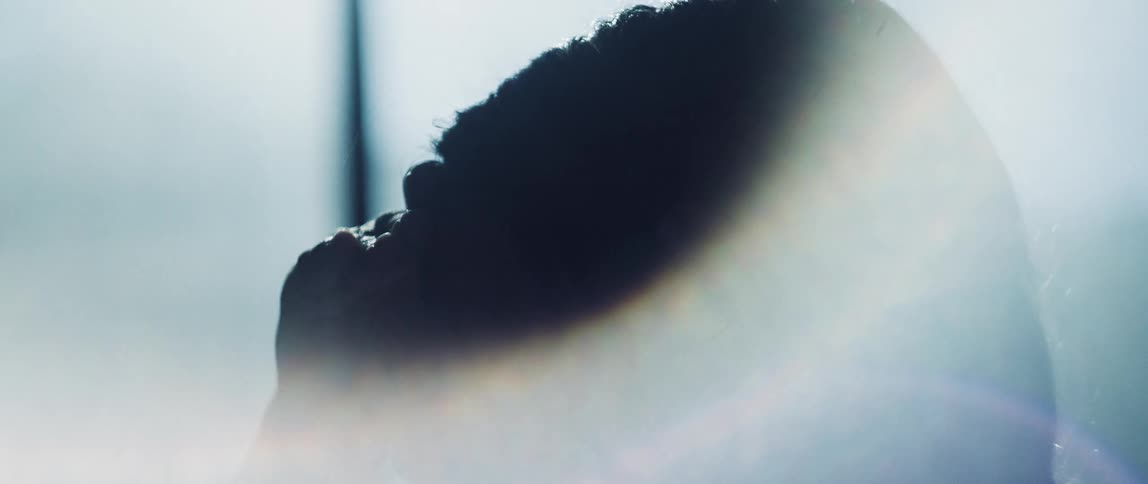 Womans head and hand is silhouetted against the office windows