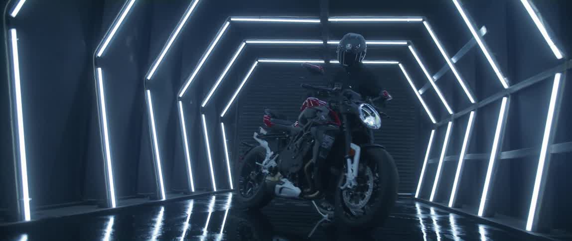 A man is walking towards a motorcycle in an indoor room