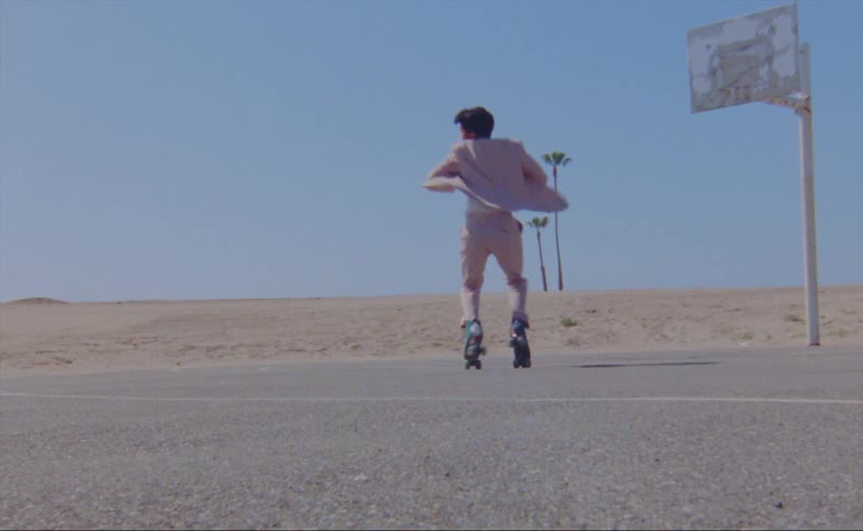 A man is dancing in roller skates by the basketball hoop
