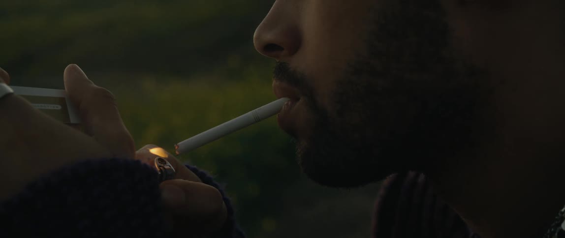 Close up of man lighting a cigarette with a lighter outdoors
