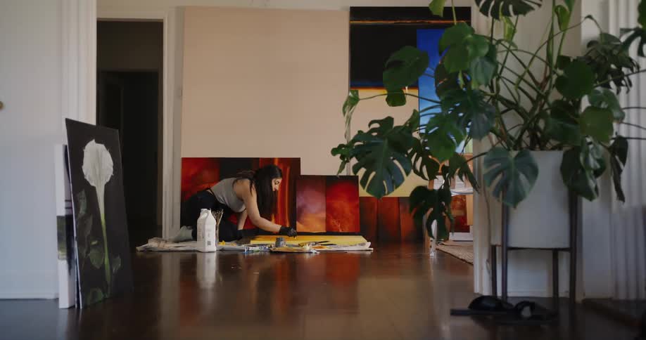 A woman paints on the floor of her living room