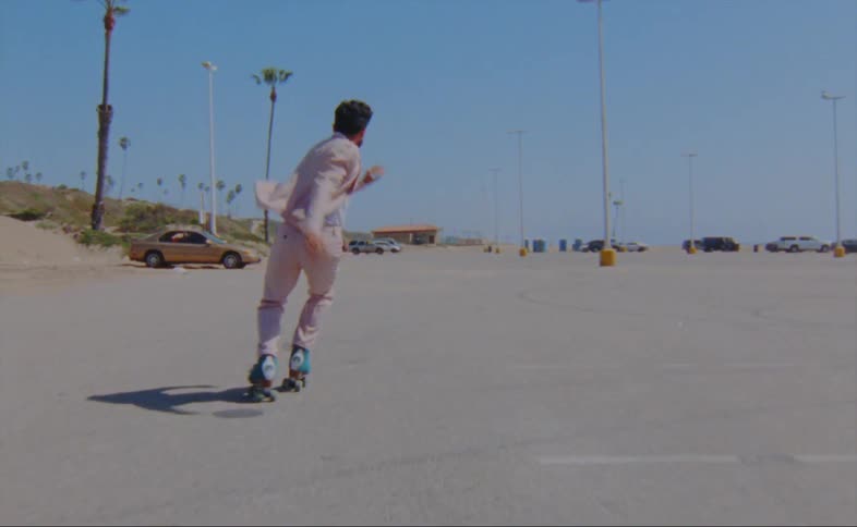 A man is skating in a parking lot during the spring time