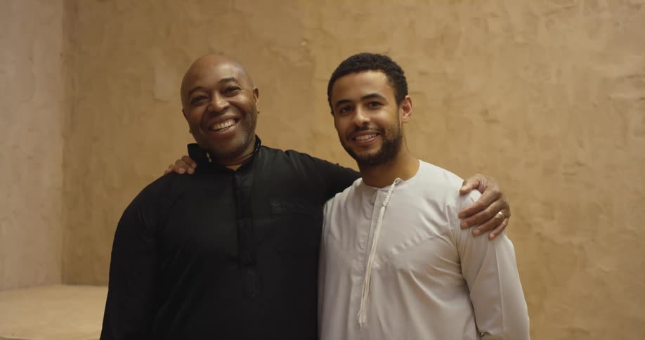 Two men are posing with their arms on each others shoulders and smiling