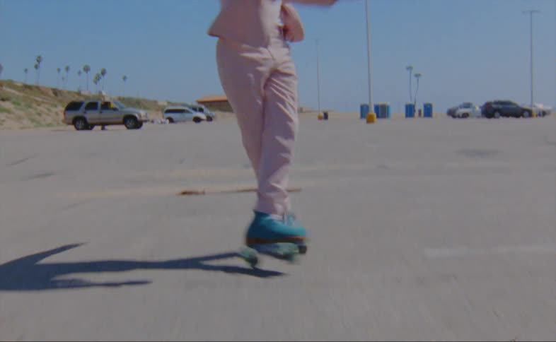 Man with pink suit roller skating over asphalt road