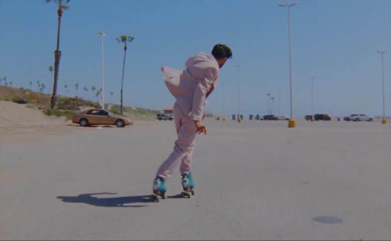 A man is skating in a parking lot during the spring