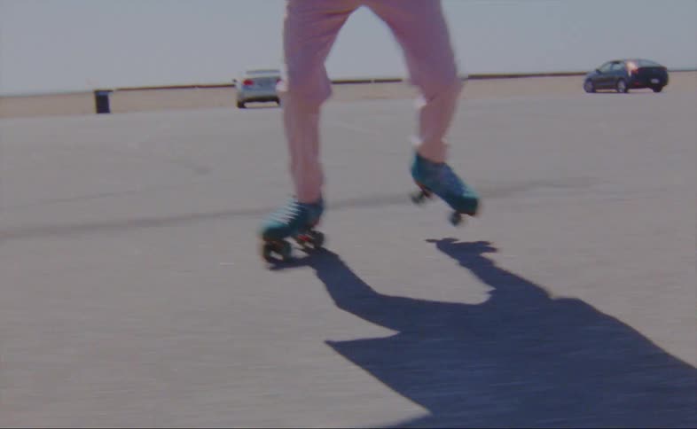 Person roller skates across parking lot bordered by sand