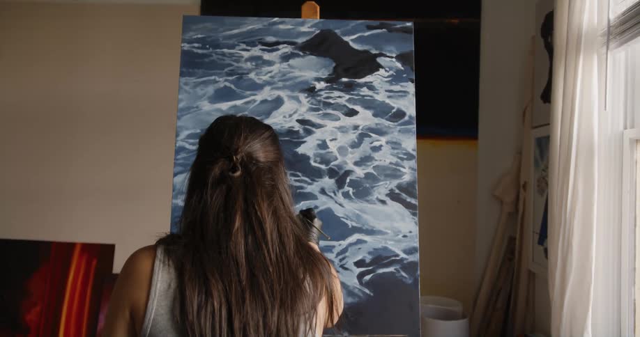 A woman is painting on the canvas