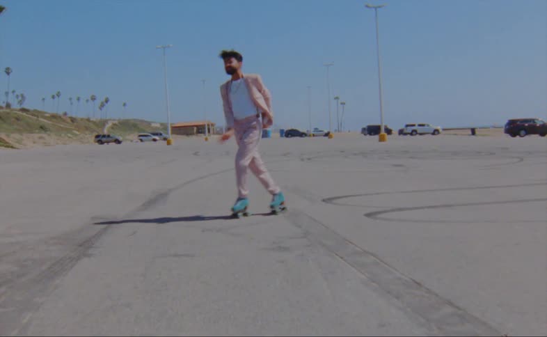 A man is roller skating in the parking lot