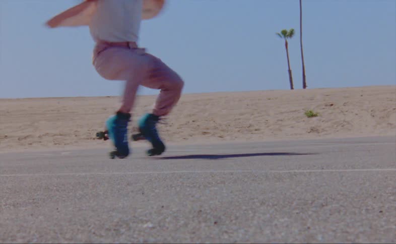 A man on rollerblades spins in circles as he bends down towards the ground