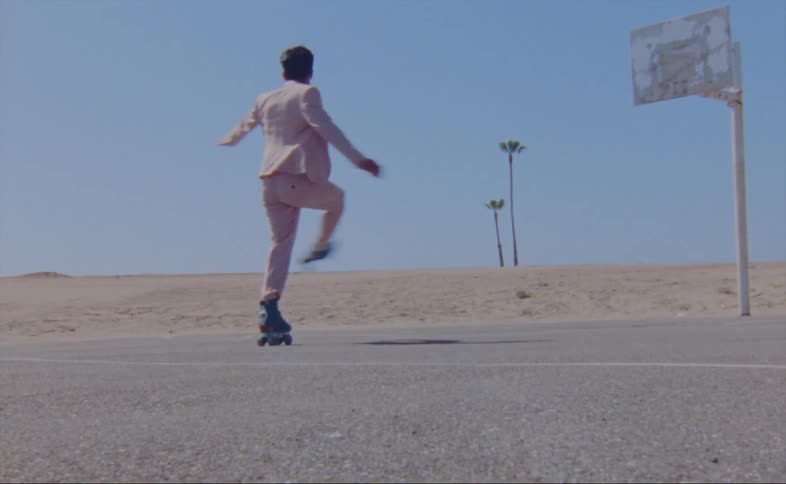 A man spins and dances on roller skates in a parking lot