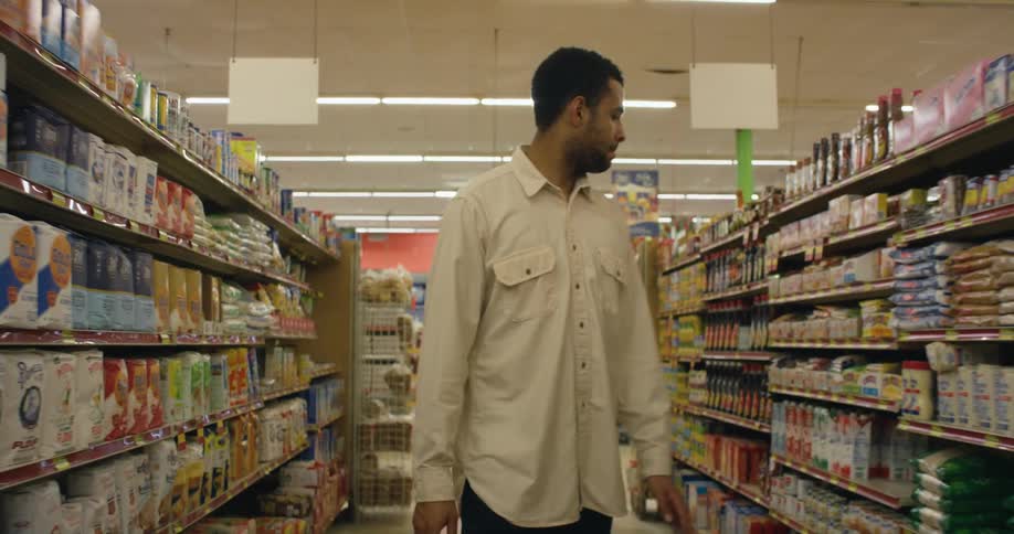 A man is walking down an aisle in a grocery store