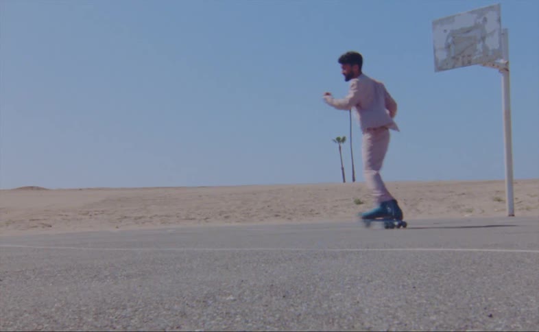 Man dances on roller skates on basketball court near sand
