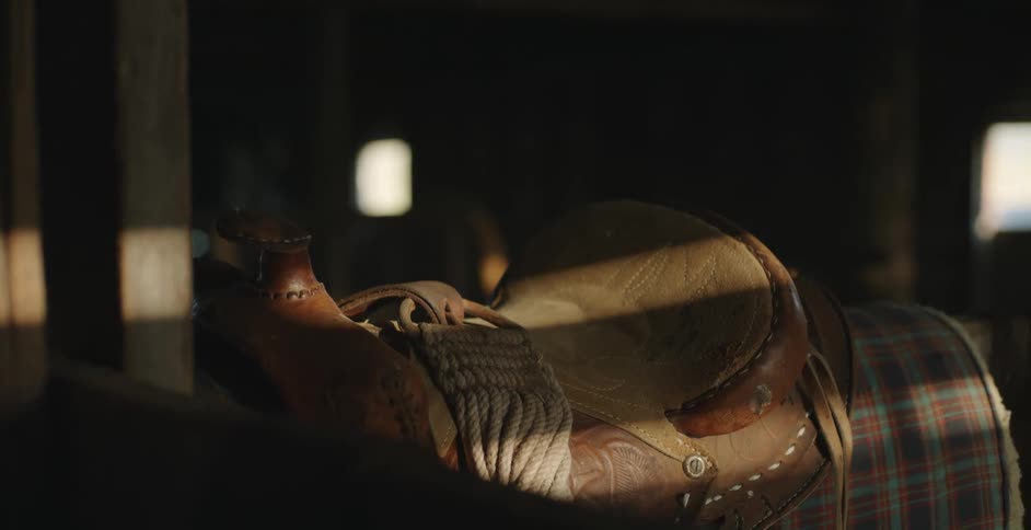 A saddle is shown in a barn at a farm