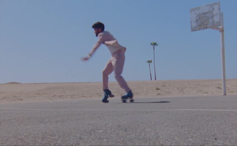 A man dances in a parking lot on roller skates