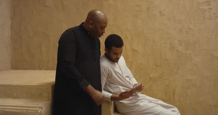 Two mean wearing white and black robes reading together