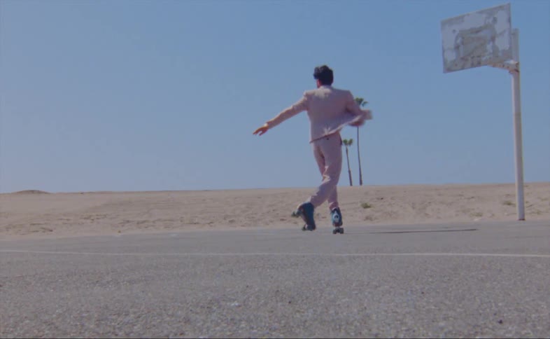 A man dances while roller skating on an outdoor basketball court on a sunny day