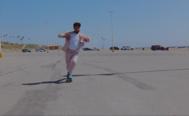 A man is skating in a parking lot during the spring