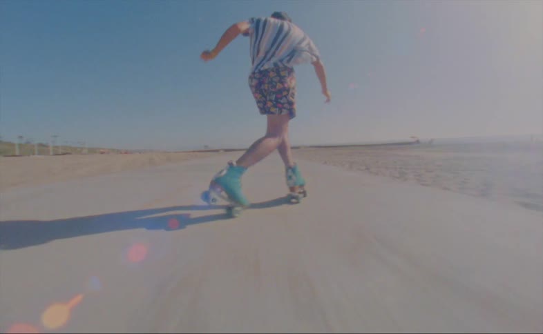 A man roller skates next to a beach