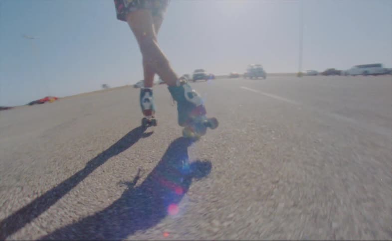 A man dances in roller skates in a parking lot during the day