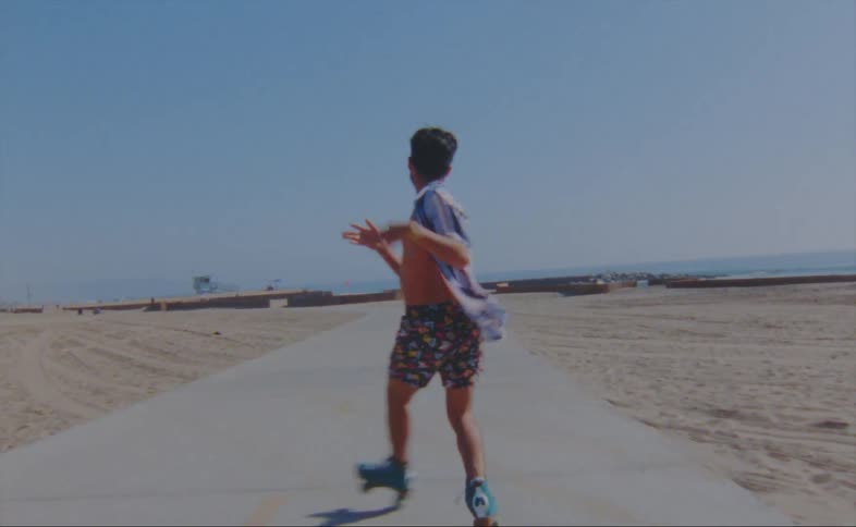 A man spins and dances on roller skates on the beach