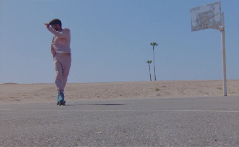 A man is near a basketball hoop skating and doing spins