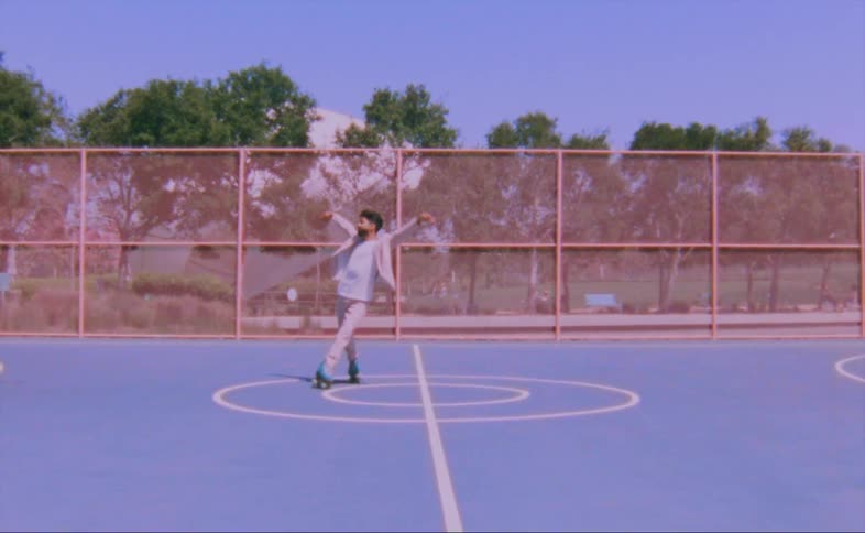 Man with beard pink suit white shirt and blue roller skates moving over ground in the court