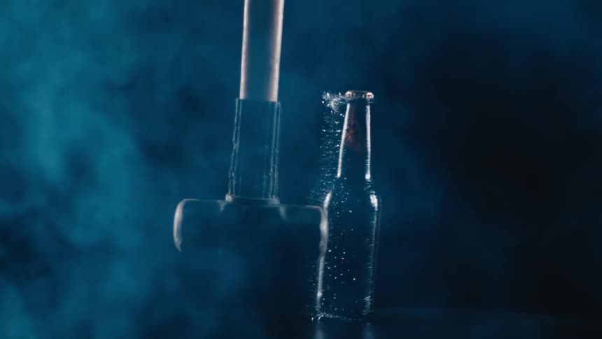 Sledge hammer knocking of a glass beer bottle in slow motion