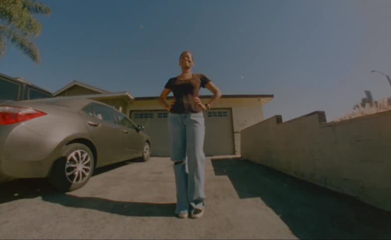 A woman is standing in her driveway and smiling