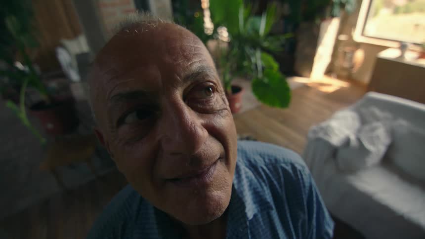 An elderly man smiles as he prays in a room