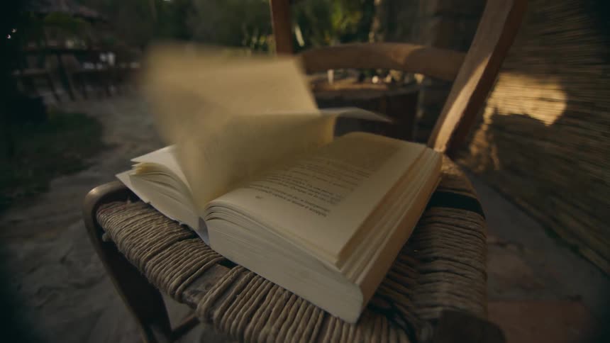 A fan is blowing pages of a book on a table and they are turning