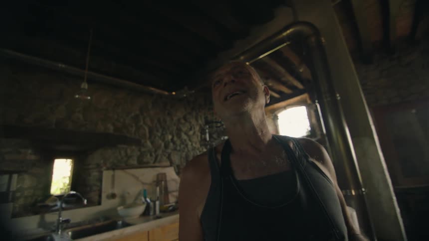 Elderly man wearing an apron talking in the cabin kitchen