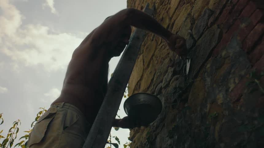 A man is putting plaster on the stone wall