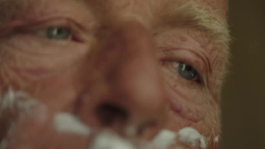 Close up of elderly man shaving with a razor aggressively