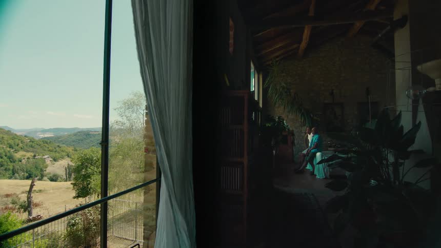 Two men sitting on a bed looking out the windows at the land below
