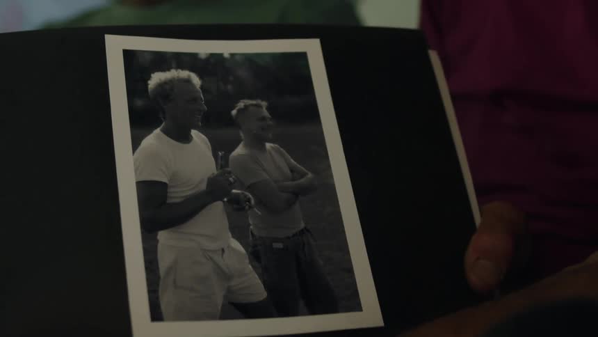 A man holds a photo of two men smiling