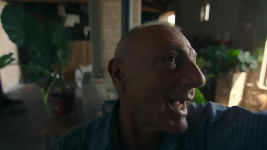 A man speaks into a mounted camera at his home