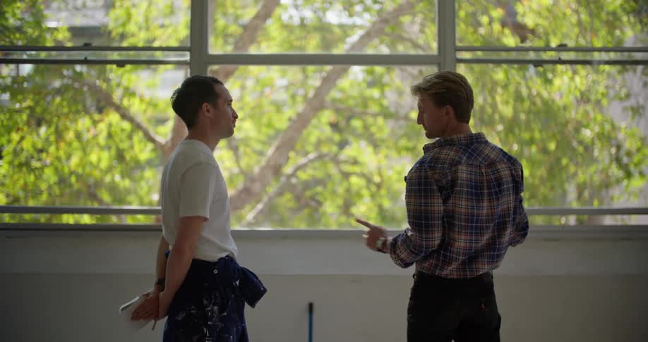 Man gestures as he discusses what he want while a man splattered with paint listens