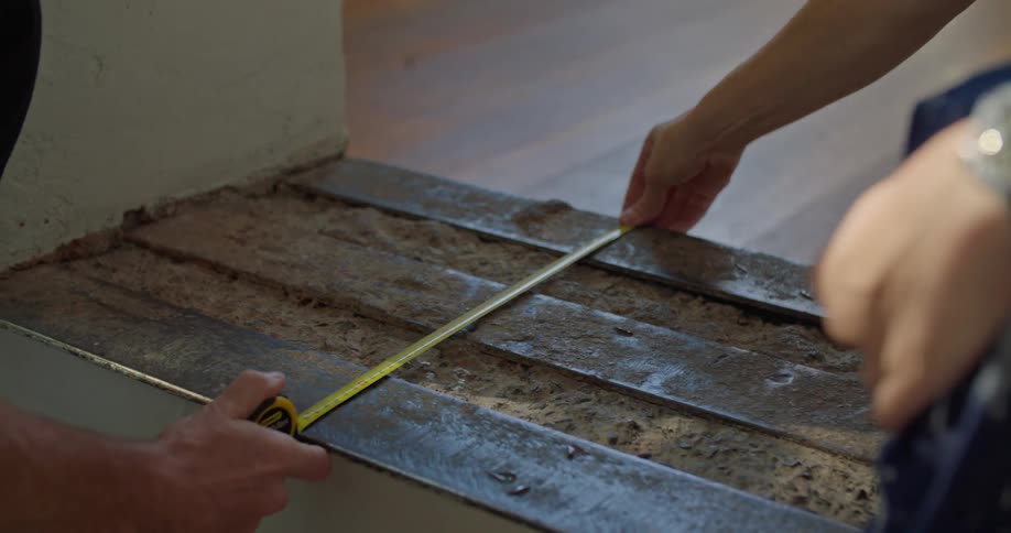 Men measure wall using self retracting metal tape measure