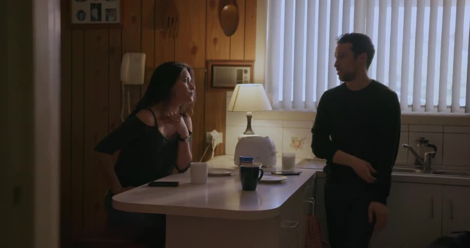 A man and woman gather at a kitchen counter with a dog