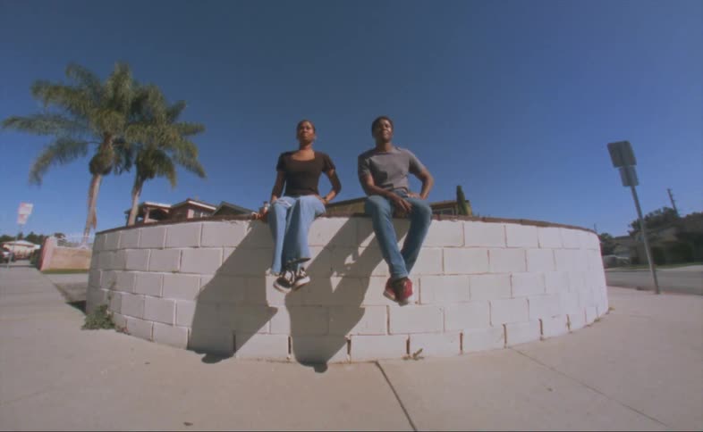 A man and woman are sitting on a block wall posing for pictures