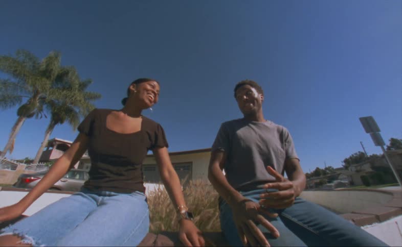 A man and woman happily talk together while sitting outdoors in a residential neighborhood during the day