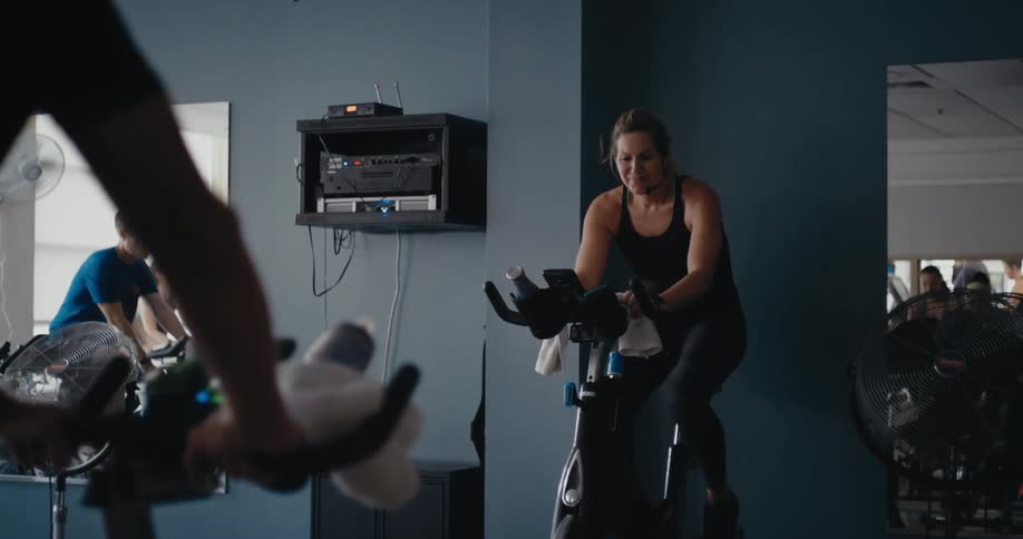Women and men work out and ride exercise bikes in the gym