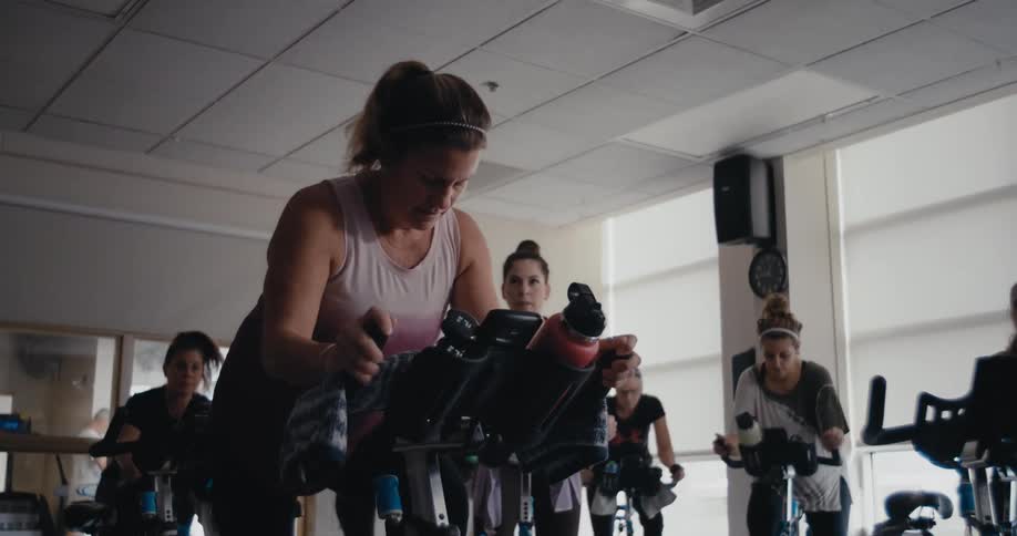 Women work out and ride exercise bikes in the gym